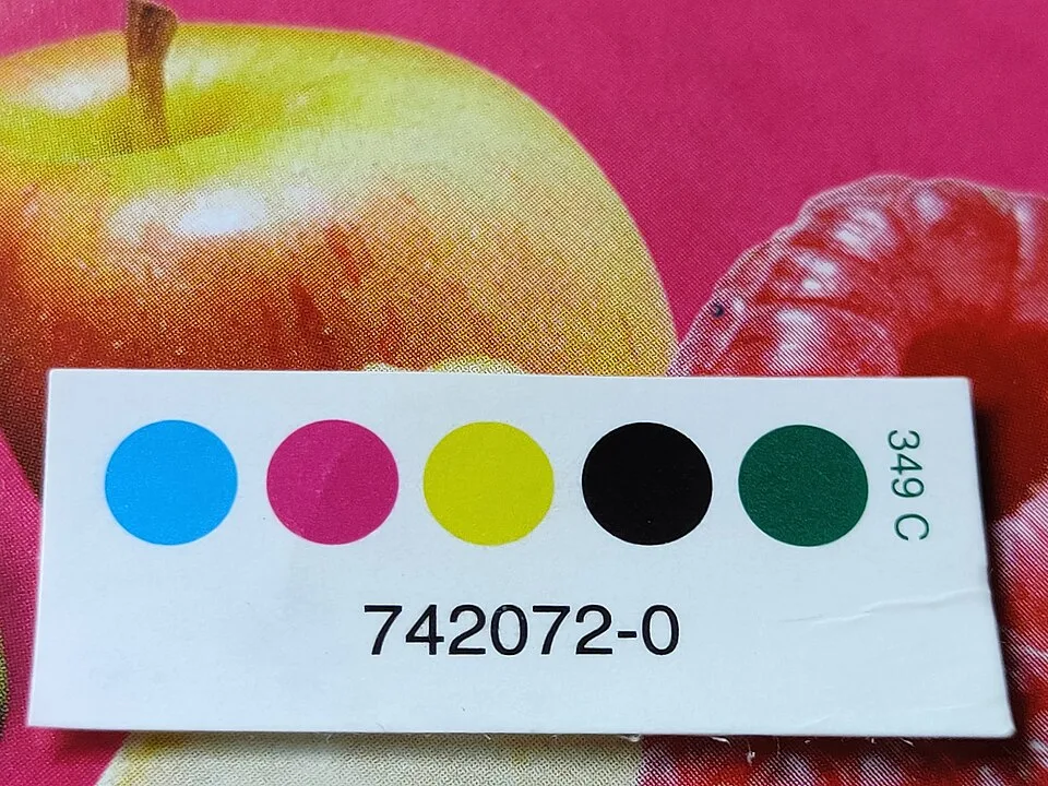 A colour control patch on packaging: four process-ink dots and a fifth spot-colour dot