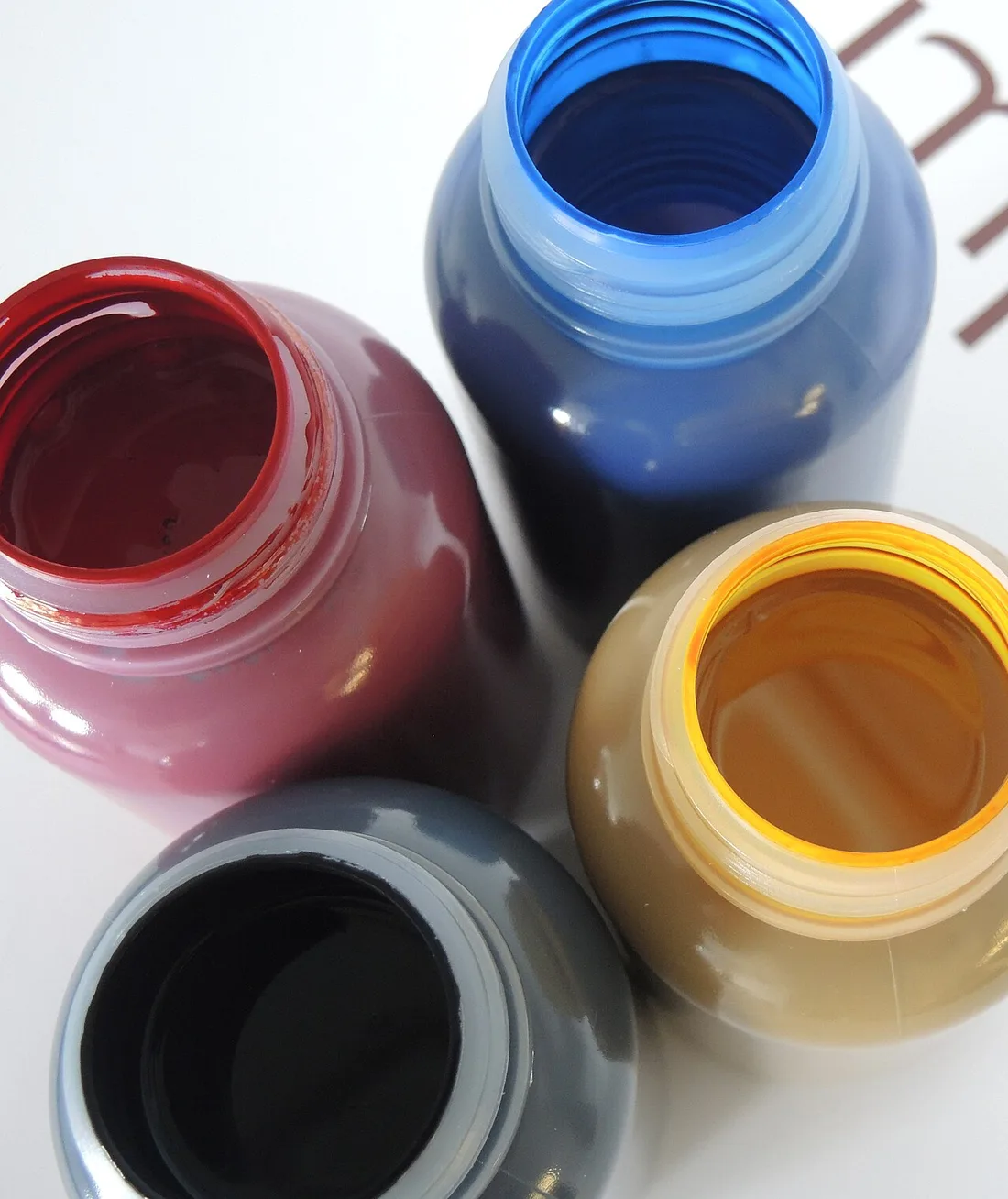 Four open bottles of printing ink: magenta, cyan, yellow and black