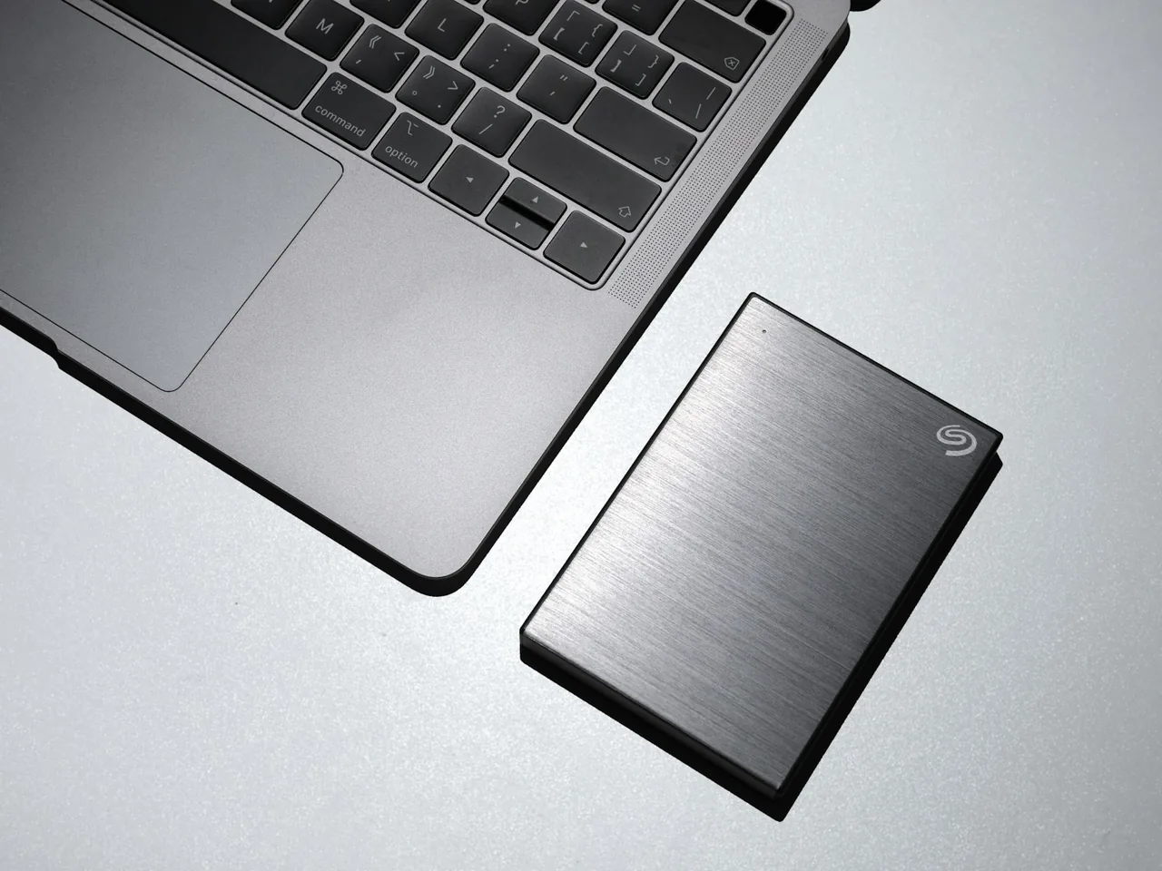 A portable external drive lying next to an open laptop