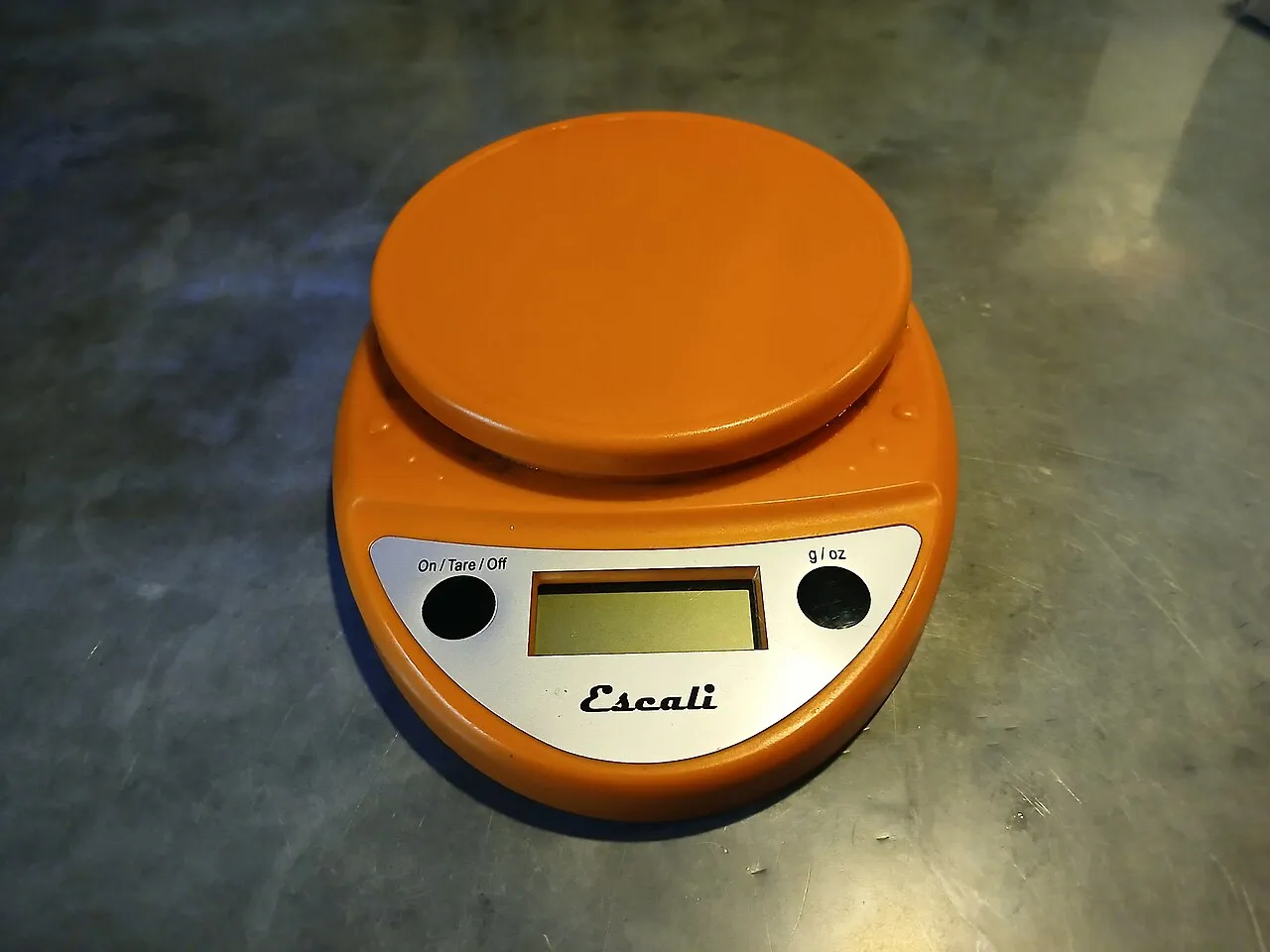 Digital kitchen scale with a button marked g / oz next to the display