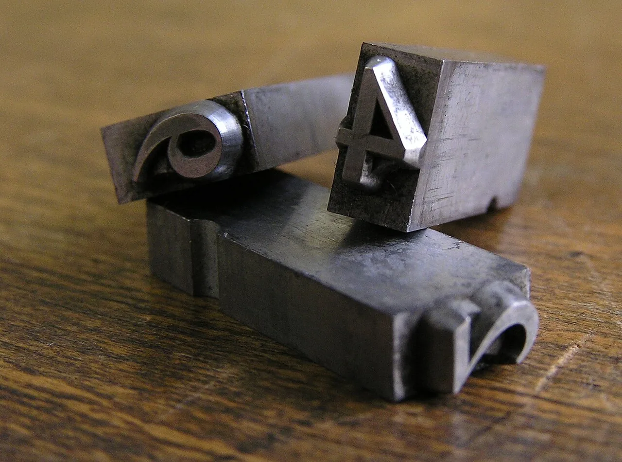 Three metal type sorts with numerals on their faces