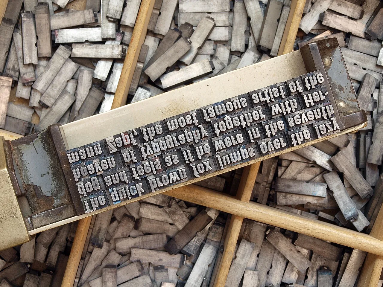 A composing stick holding several lines of metal type of equal length