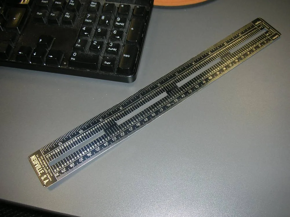 A typometer with several scales lying next to a keyboard