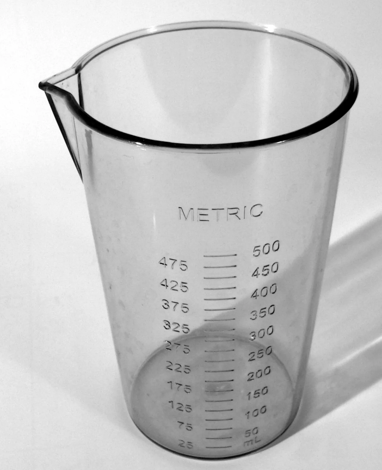 Clear measuring beaker marked METRIC with a scale up to 500 millilitres